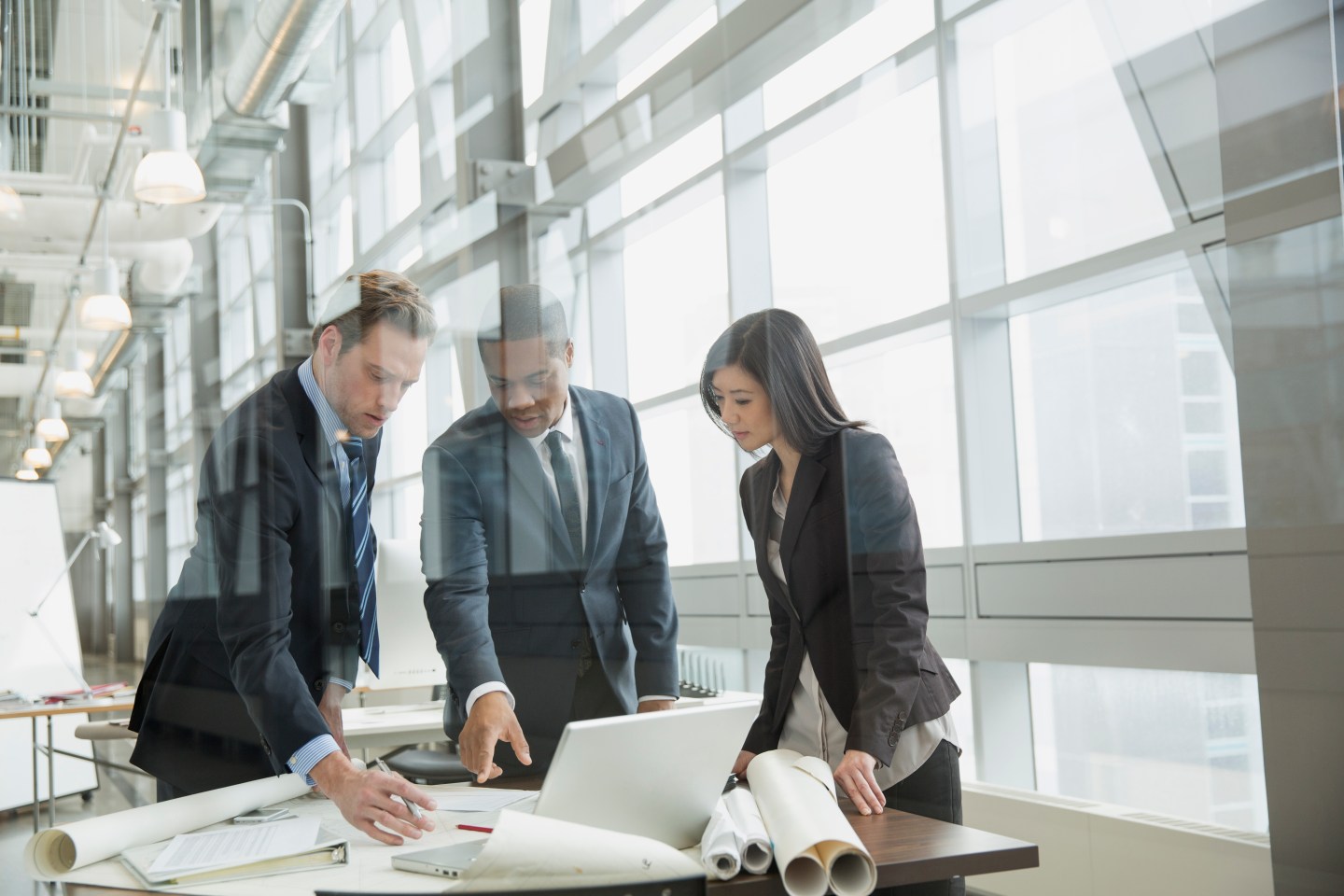 Business people reviewing blueprints at desk