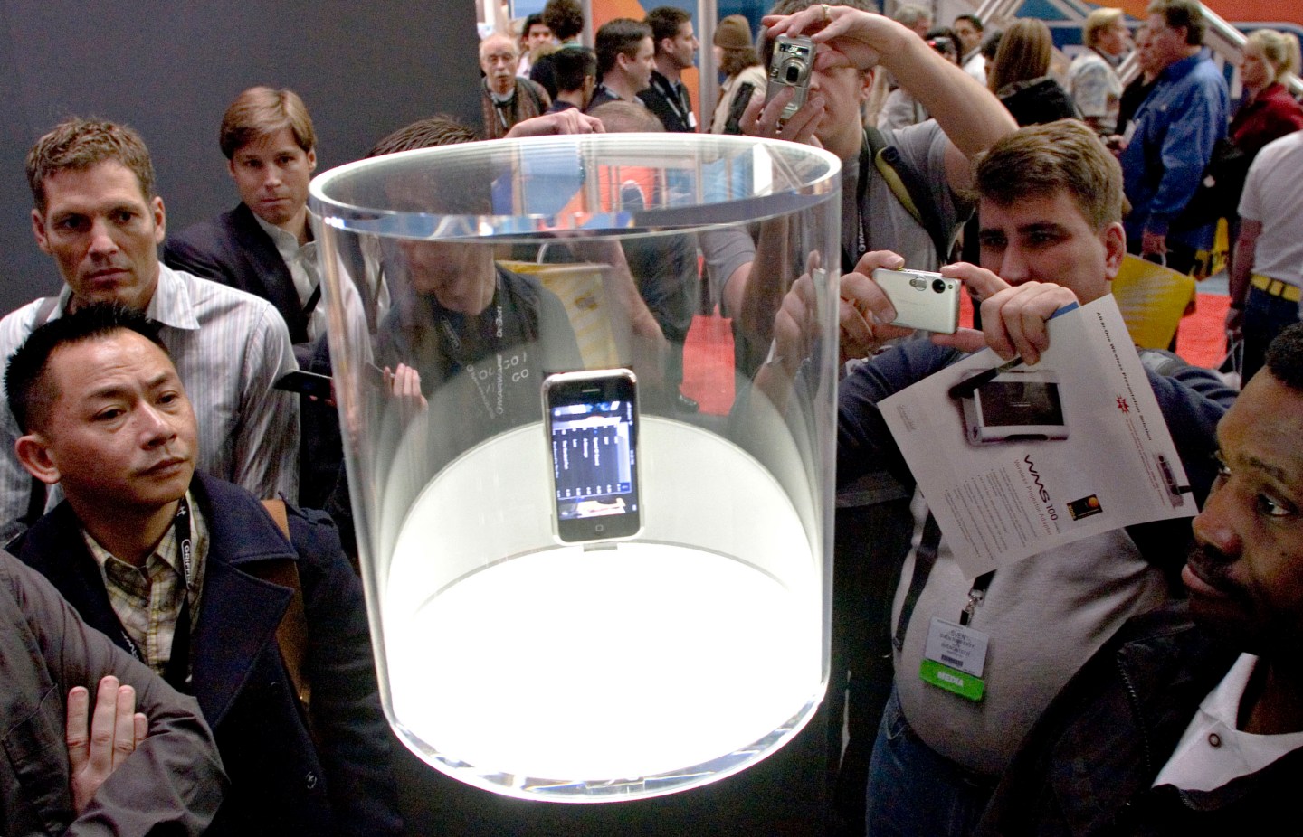 MacWorld attendees look over an iPhone on display during Mac