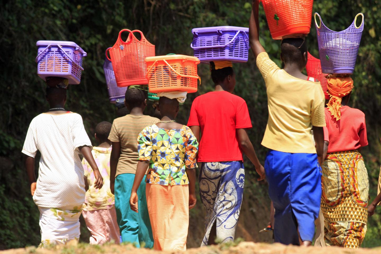 Rwandan women walk with their baskets on their heads in Cyamudon