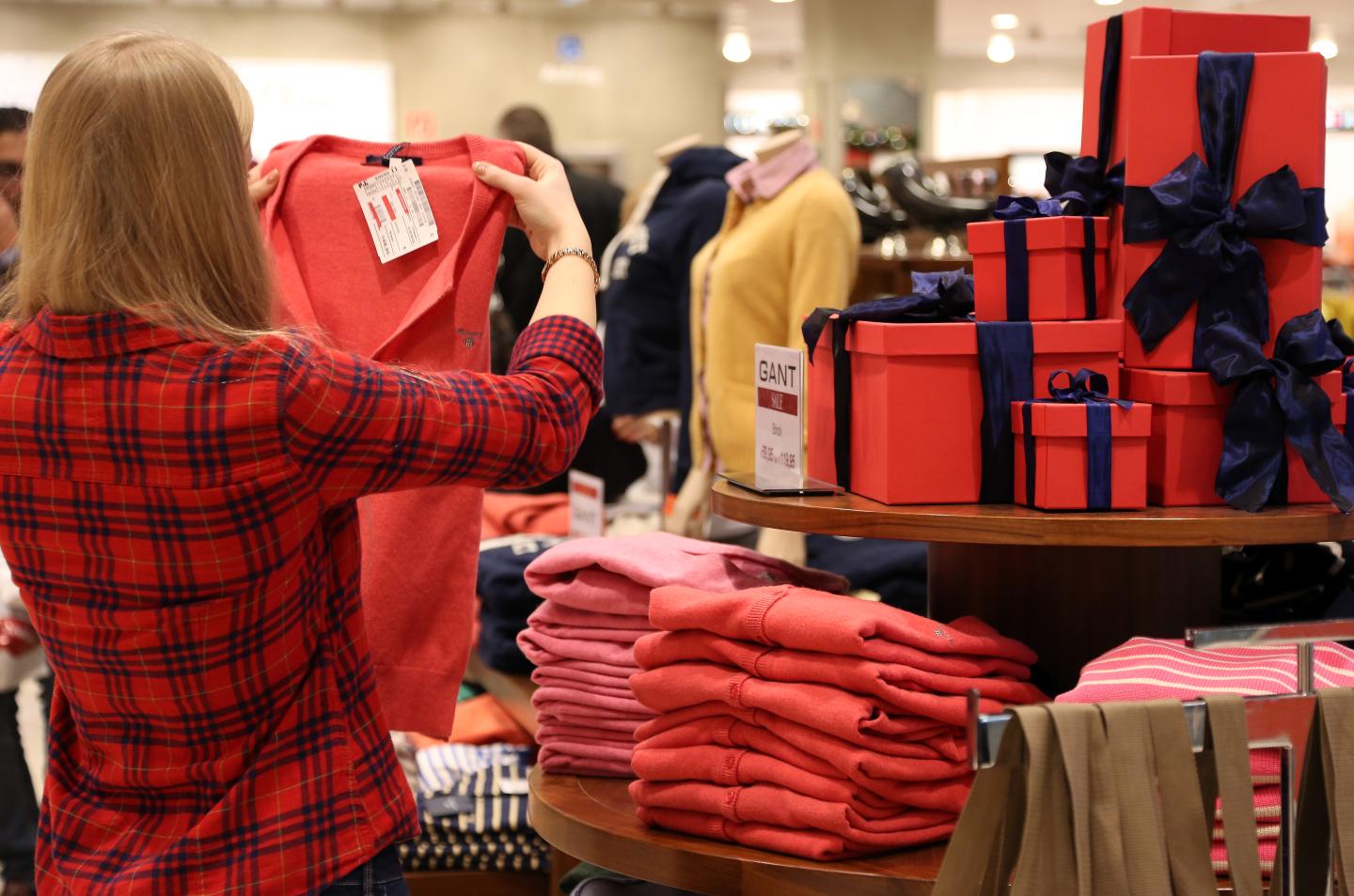 An employee arranges sweaters in a department store during the holiday season.