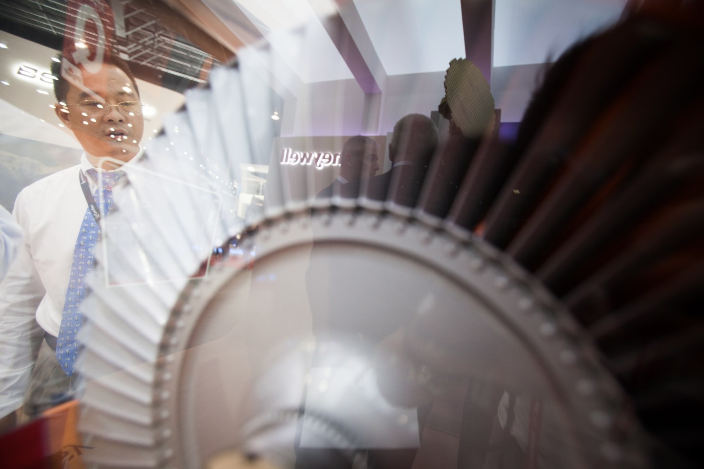 Attendees are reflected on a showcase for a Honeywell International aircraft engine.