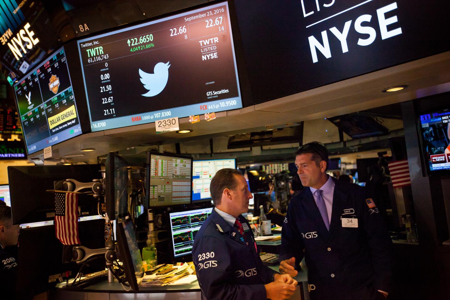 Stock traders work beneath a monitor displaying Twitter Inc. signage on the floor of the New York Stock Exchange (NYSE) in New York, U.S.