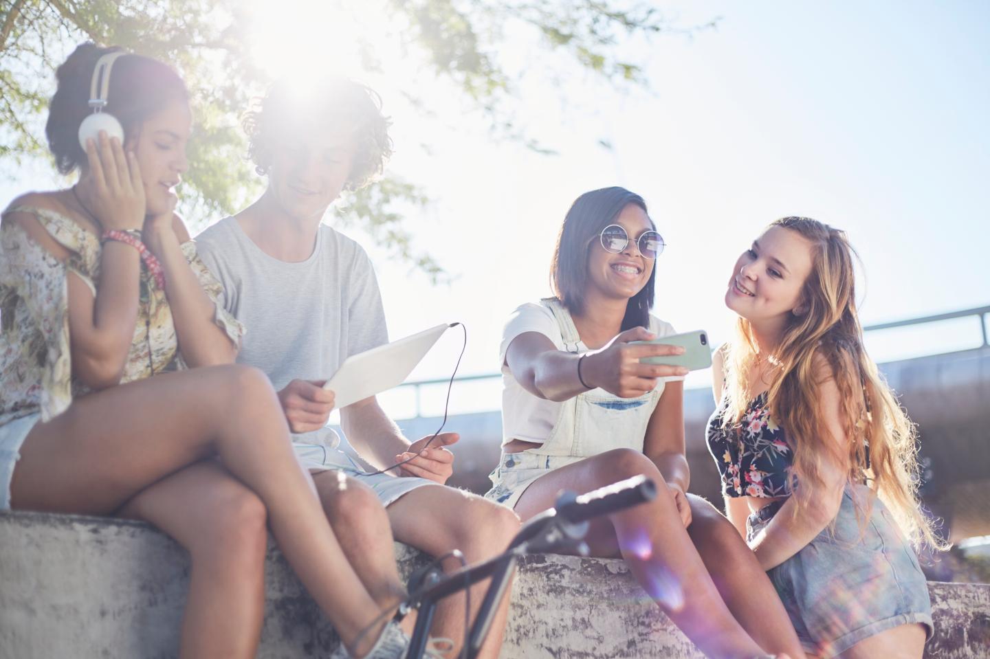 Teenage friends hanging out taking selfie and listening to music