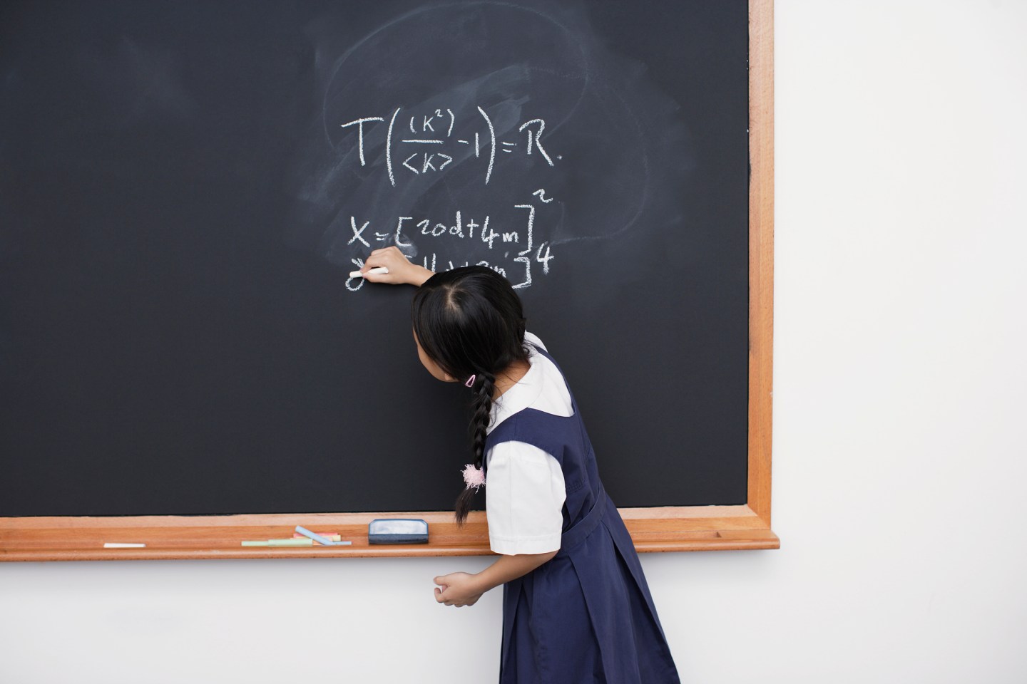 Girl writing on blackboard in classroom