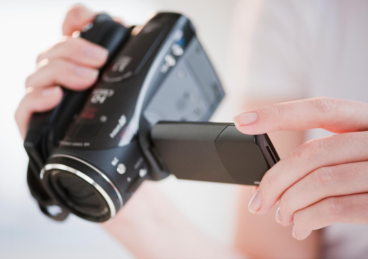 Woman using digital camcorder, close-up