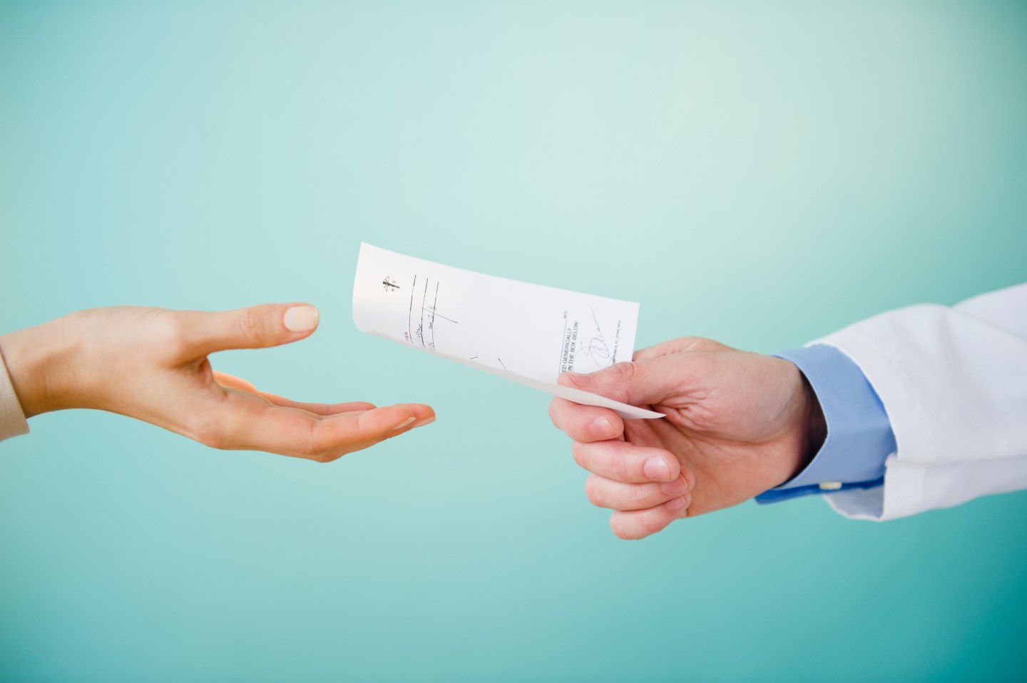 Close up of doctor's hand giving prescription to patient, studio shot