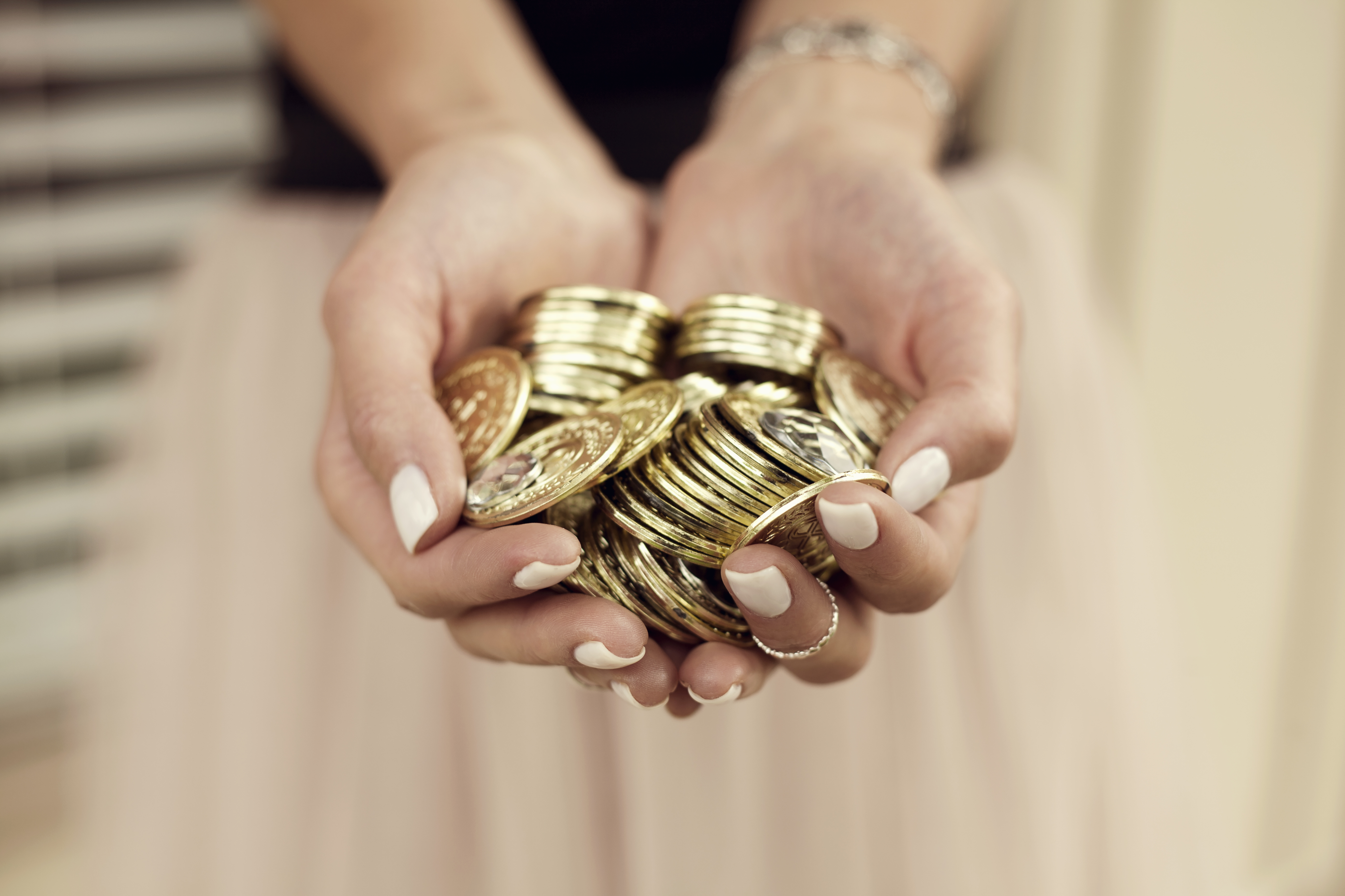Young woman with handful of gold coins, focus on hands