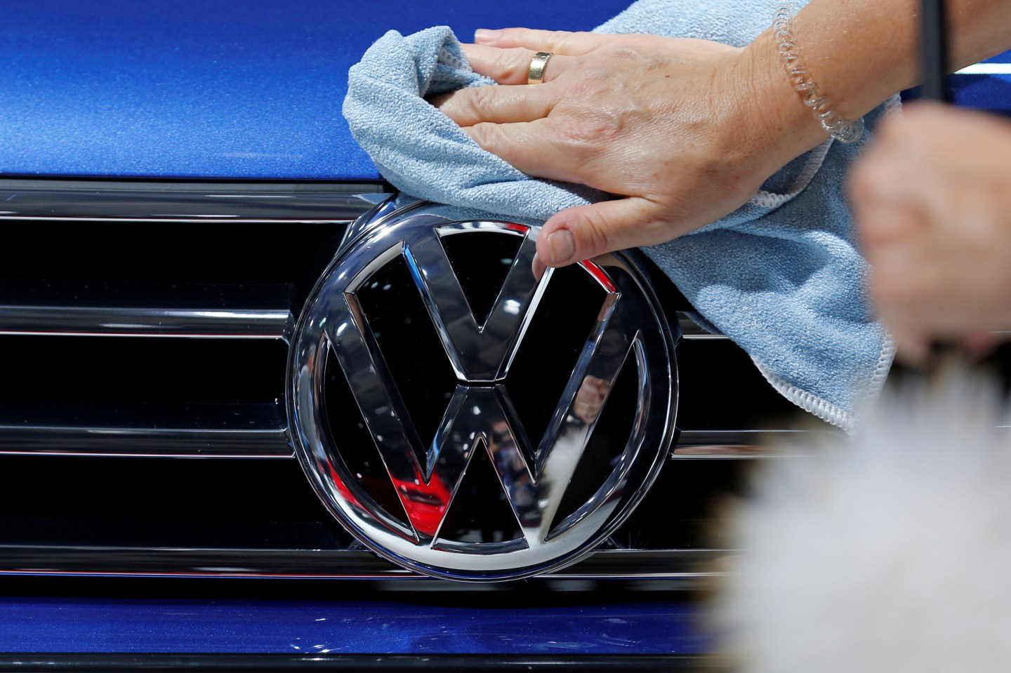 A worker shines the grill of a Volkswagen car displayed on media day at the Paris auto show, in Paris