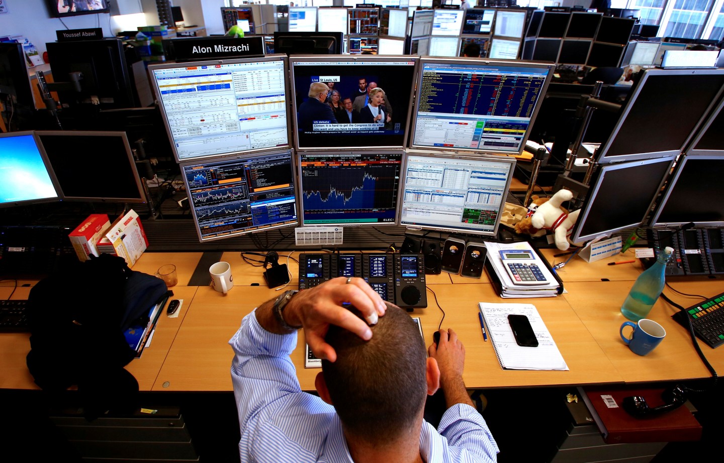 Trader Alon Mizrachi watches one of his screens the U.S. presidential town hall debate between Republican US presidential nominee Donald Trump and Democratic nominee Hillary Clinton, in central Sydney, Australia