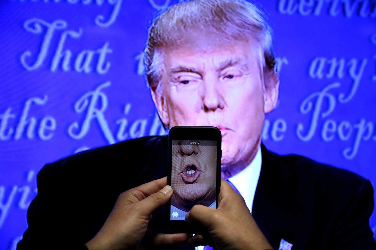 A journalist records a video from screen as Republican U.S. presidential nominee Donald Trump speaks during the first presidential debate with U.S. Democratic presidential candidate Hillary Clinton at Hofstra University in Hempstead