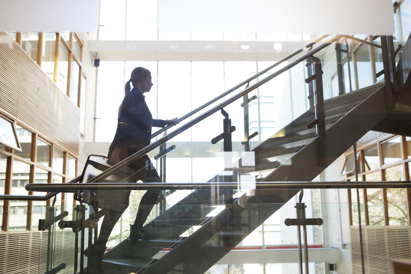 Woman walking up stairs in office building