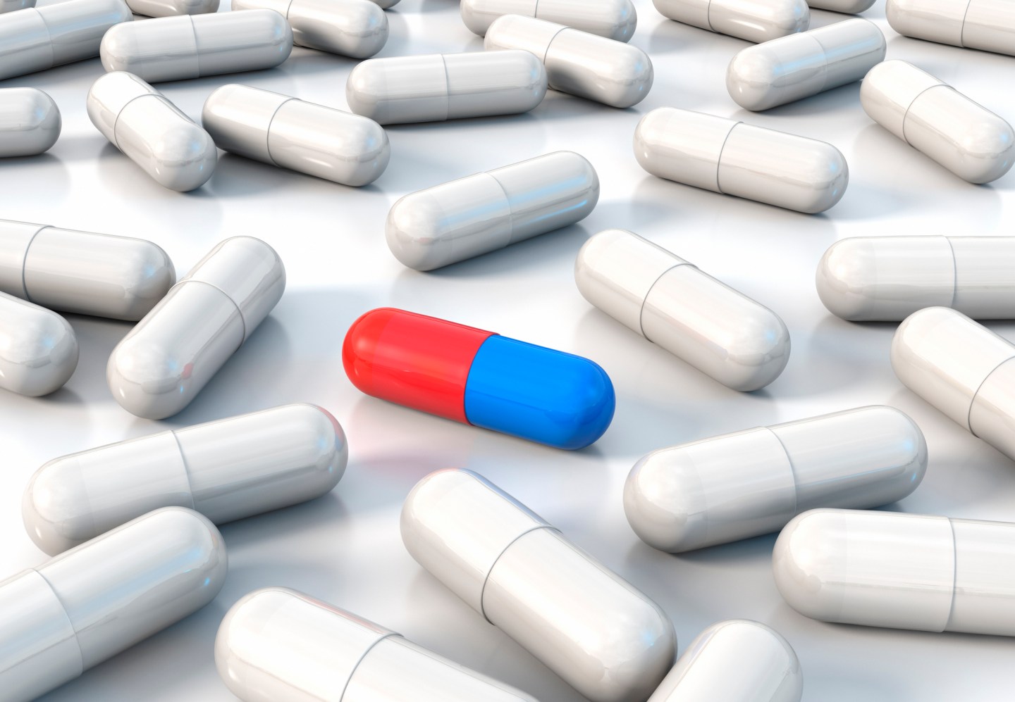 Blue and red capsule amongst plain white ones