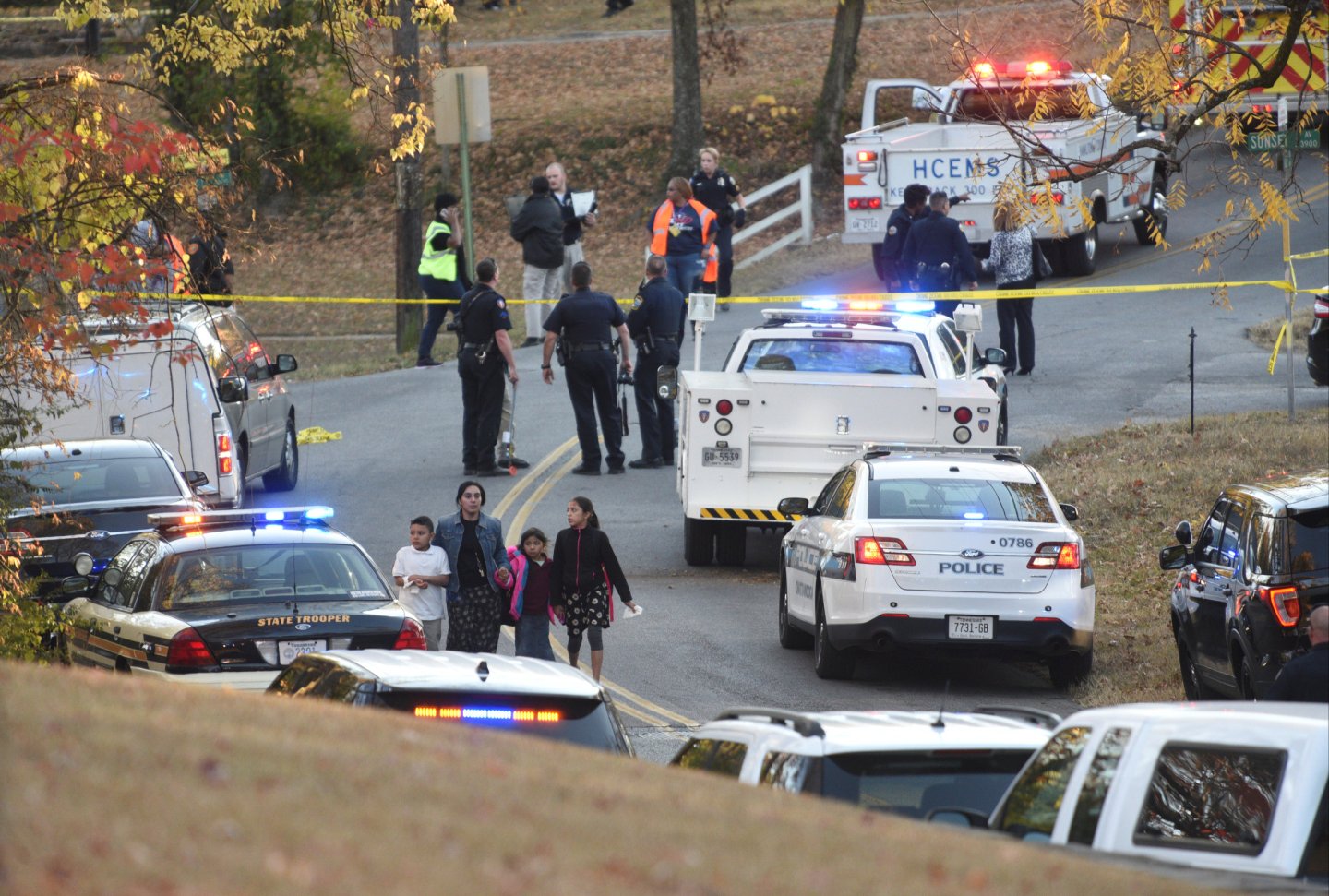A woman escorts three children away from the scene of a school bus crash involving multiple fatalities in Chattanooga