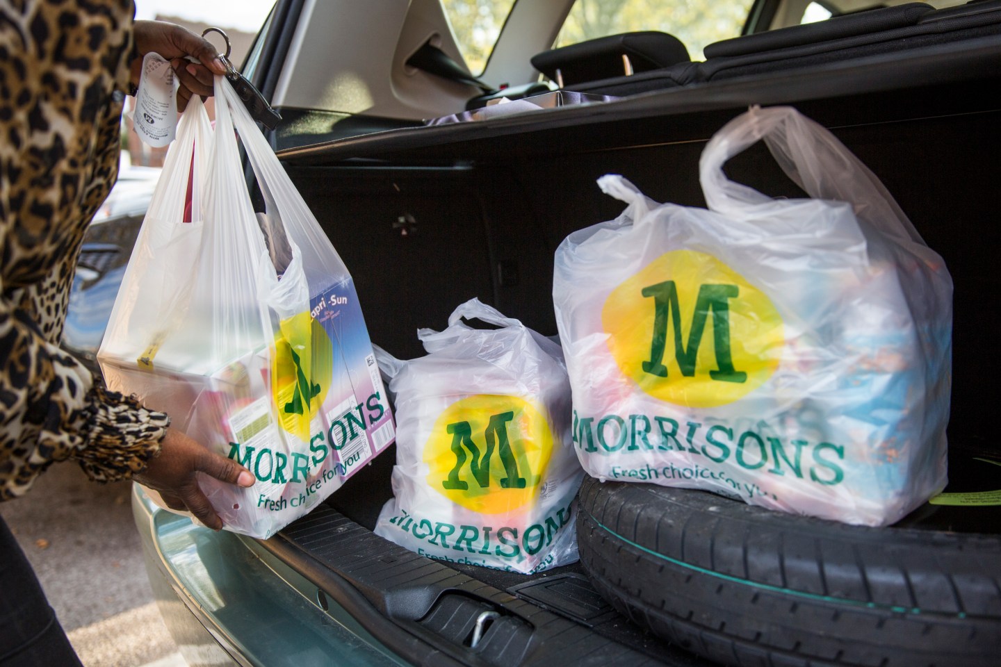 A customer places Morrison’s shopping bags in their car in London.