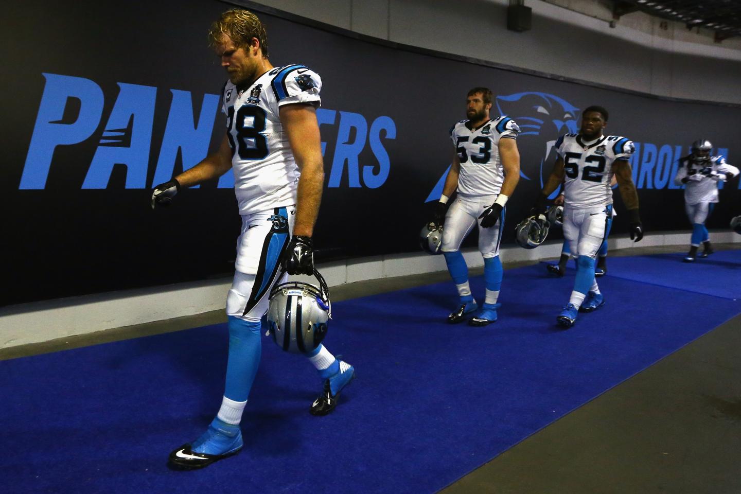 Greg Olsen #88, Ben Jacobs #53, and Kevin Reddick #52 of the Carolina Panthers return to the locker room at Bank of America Stadium.