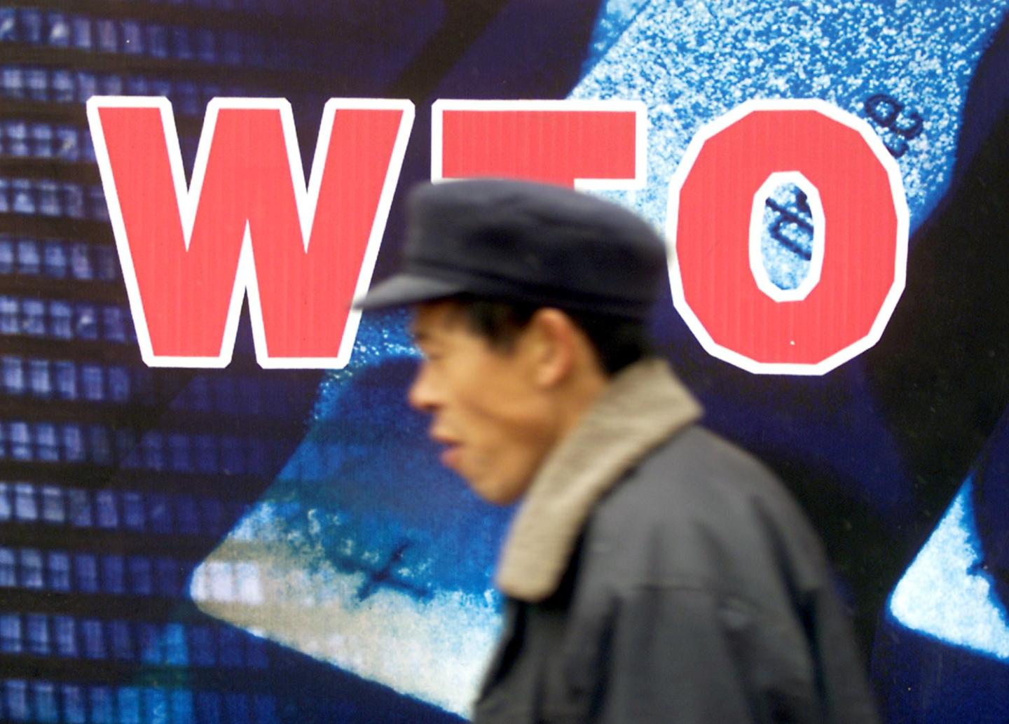 A Chinese man walks past a billboard welcoming the