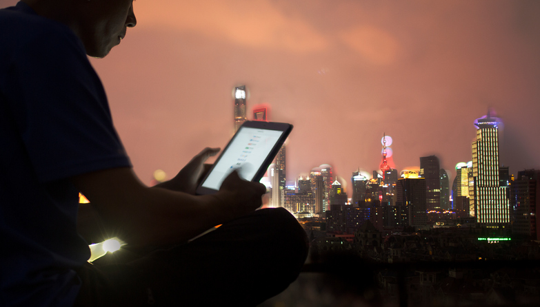 One man reading the smart phone screen on the rooftop,background is Shanghai finance building