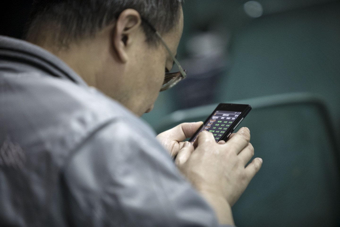 A man looks at share prices on a smartphone at a securities brokerage in Shanghai, China, on Wednesday, Nov. 9, 2016.