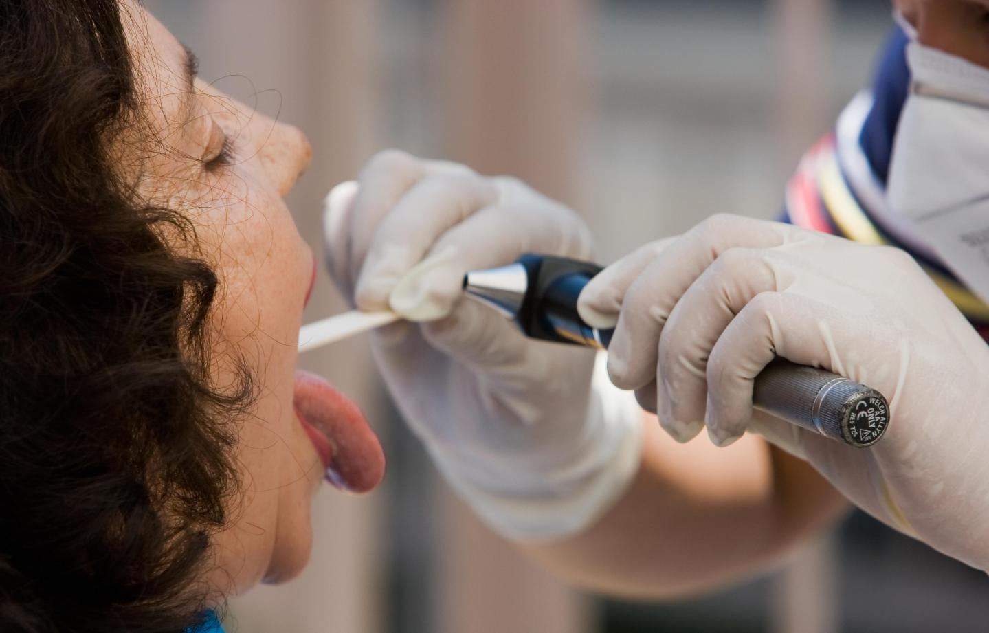 A doctor checks a pacient's throat at on