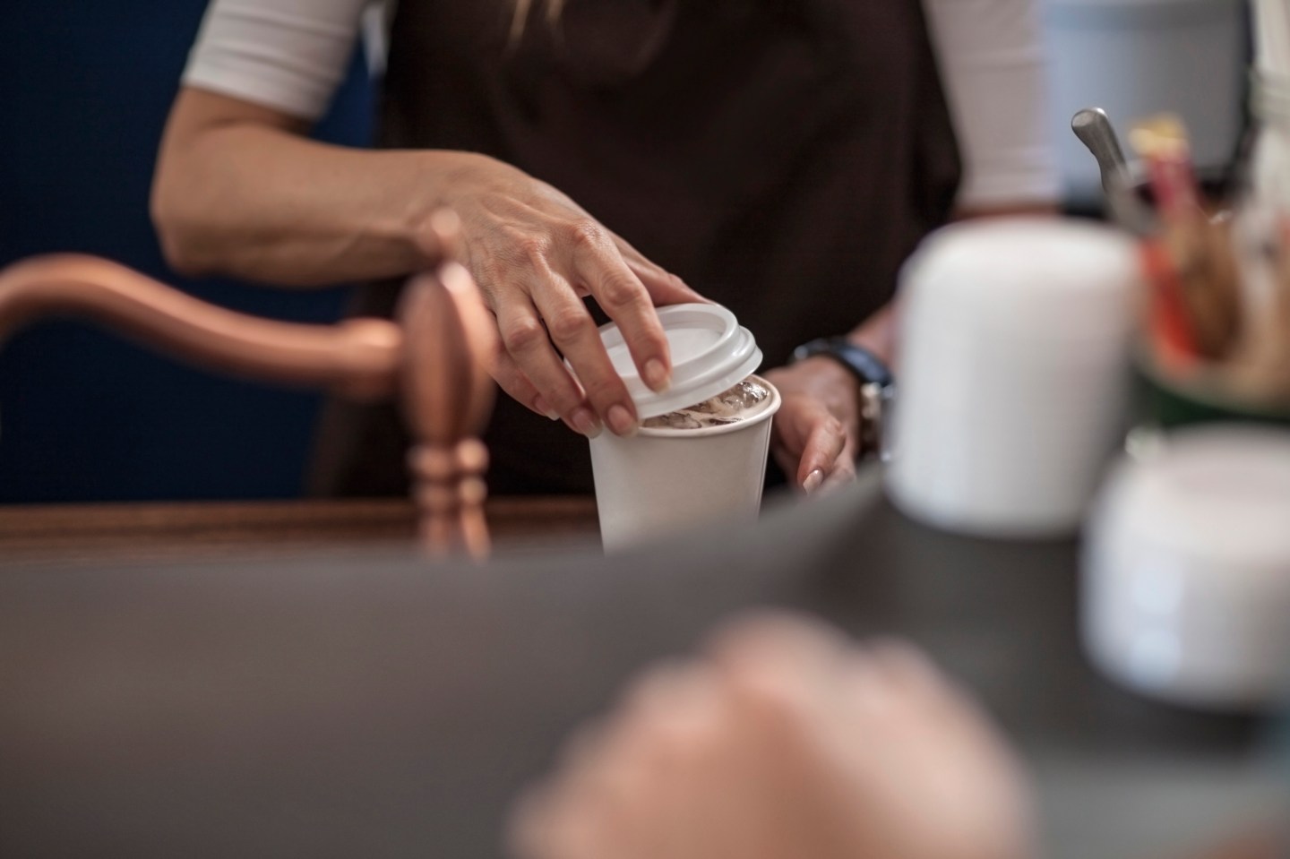 Barista closing lid of disposable coffee cup