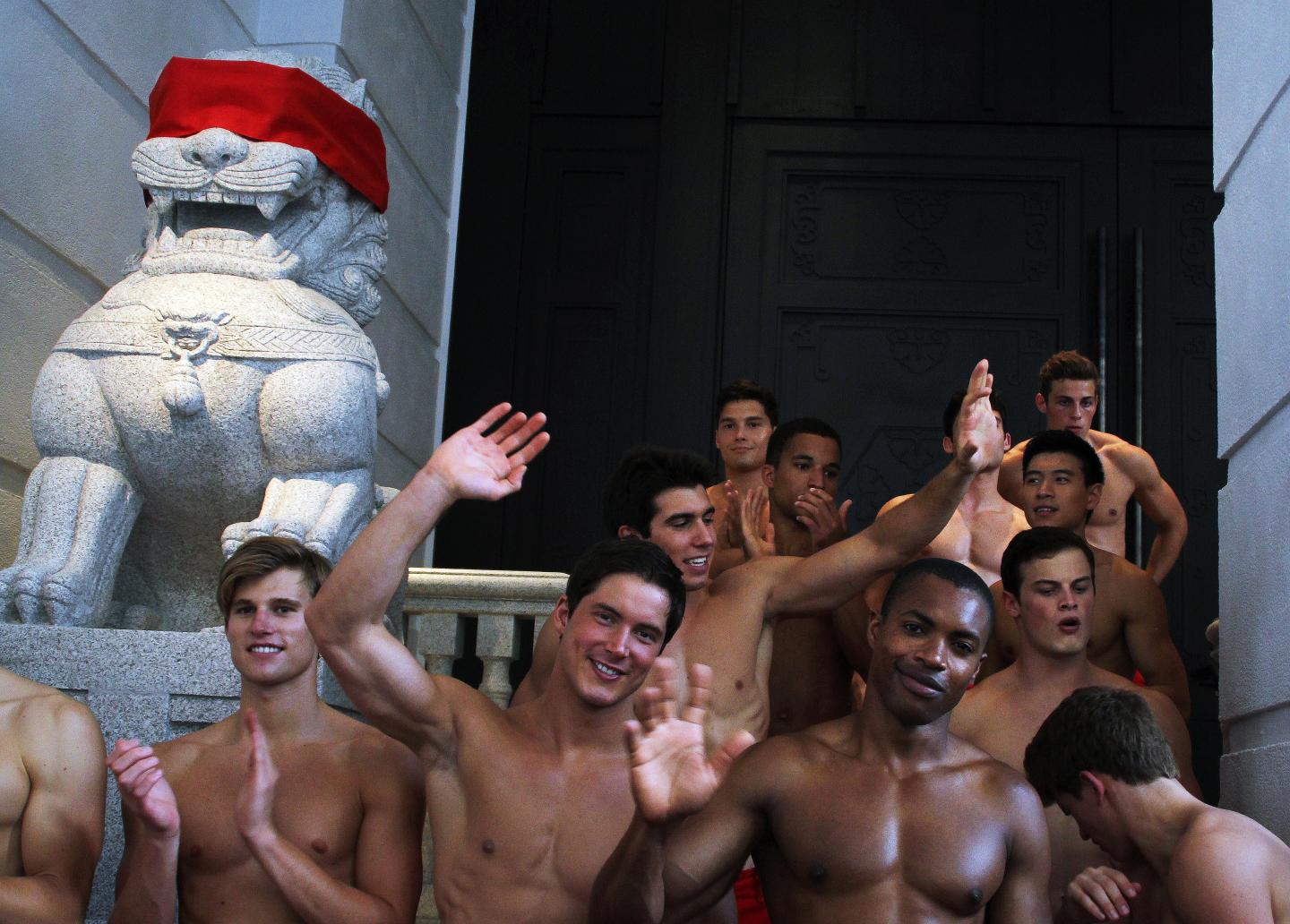 A group of topless male models waves to