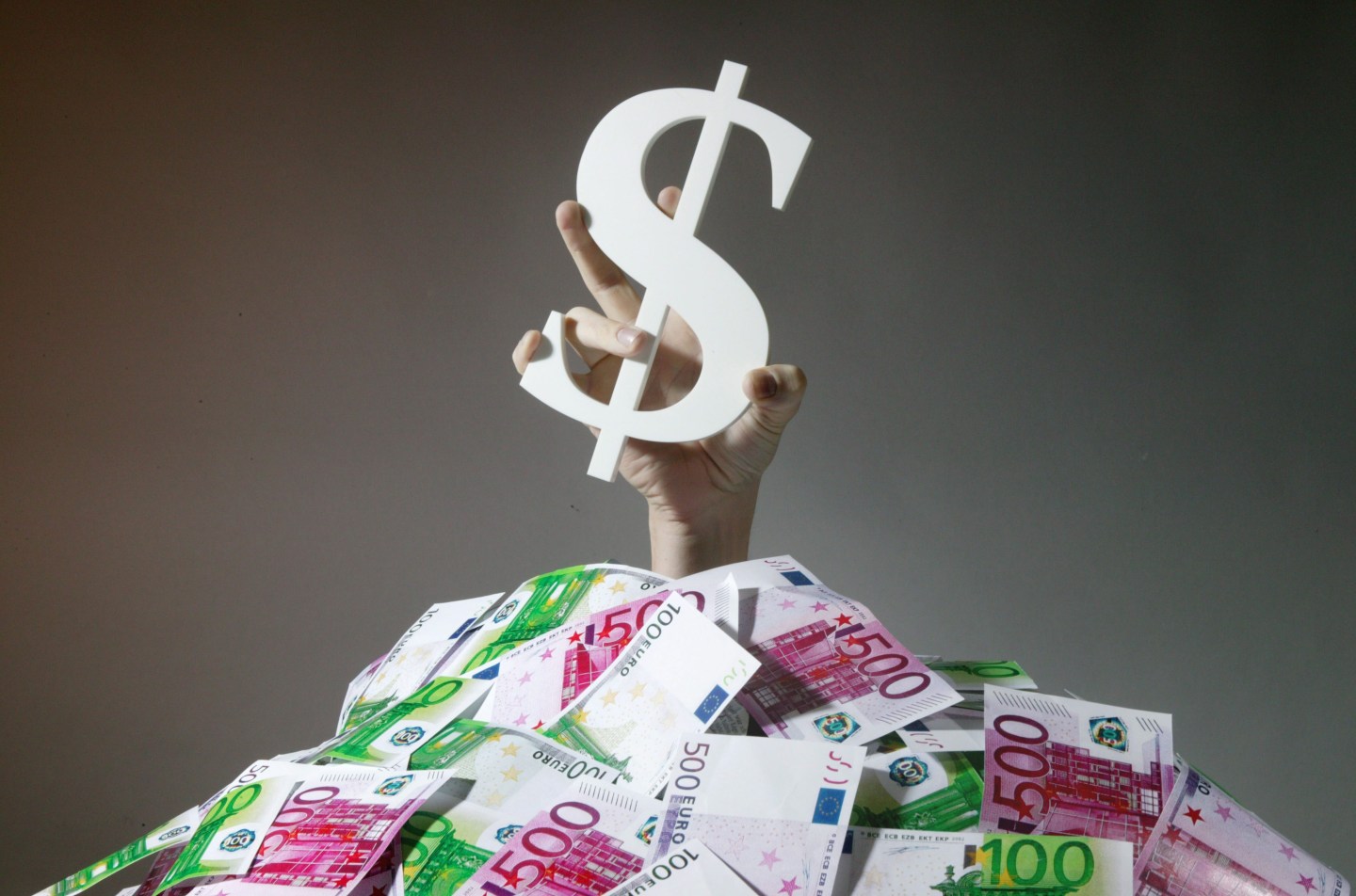 Feature: the Dollar is inundatet with Euros / price gains of the Euro against the Dollar, Hand with a Dollar sign coming out of a pile of Euro notes.