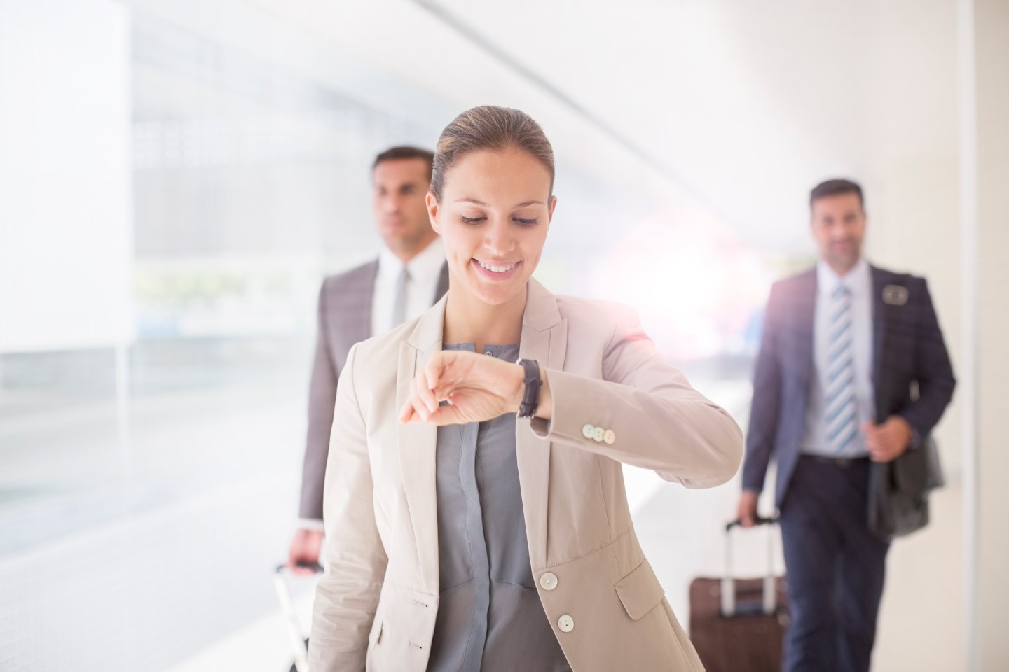 Businesswoman checking wristwatch in corridor