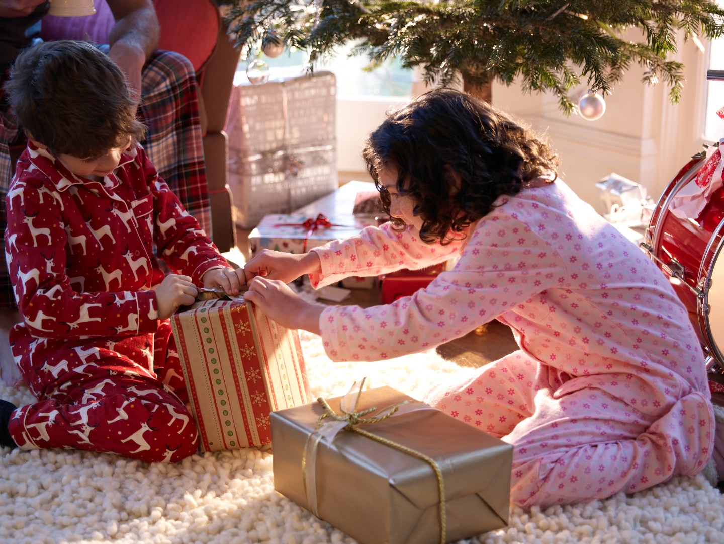 Brother and sister (6-11) unwrapping Christmas gifts