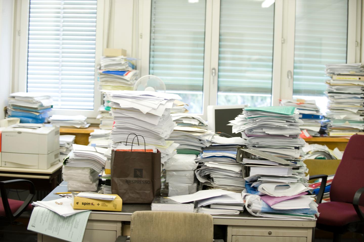 Messy desk with stacks of paperwork and binders, Cern, Geneva, Switzerland