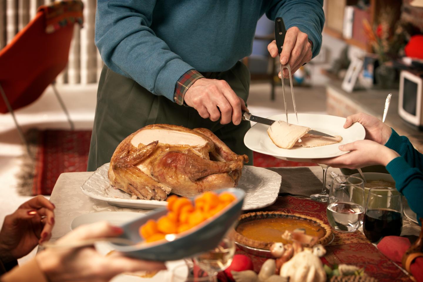 Man serving turkey at dining room table, mid section