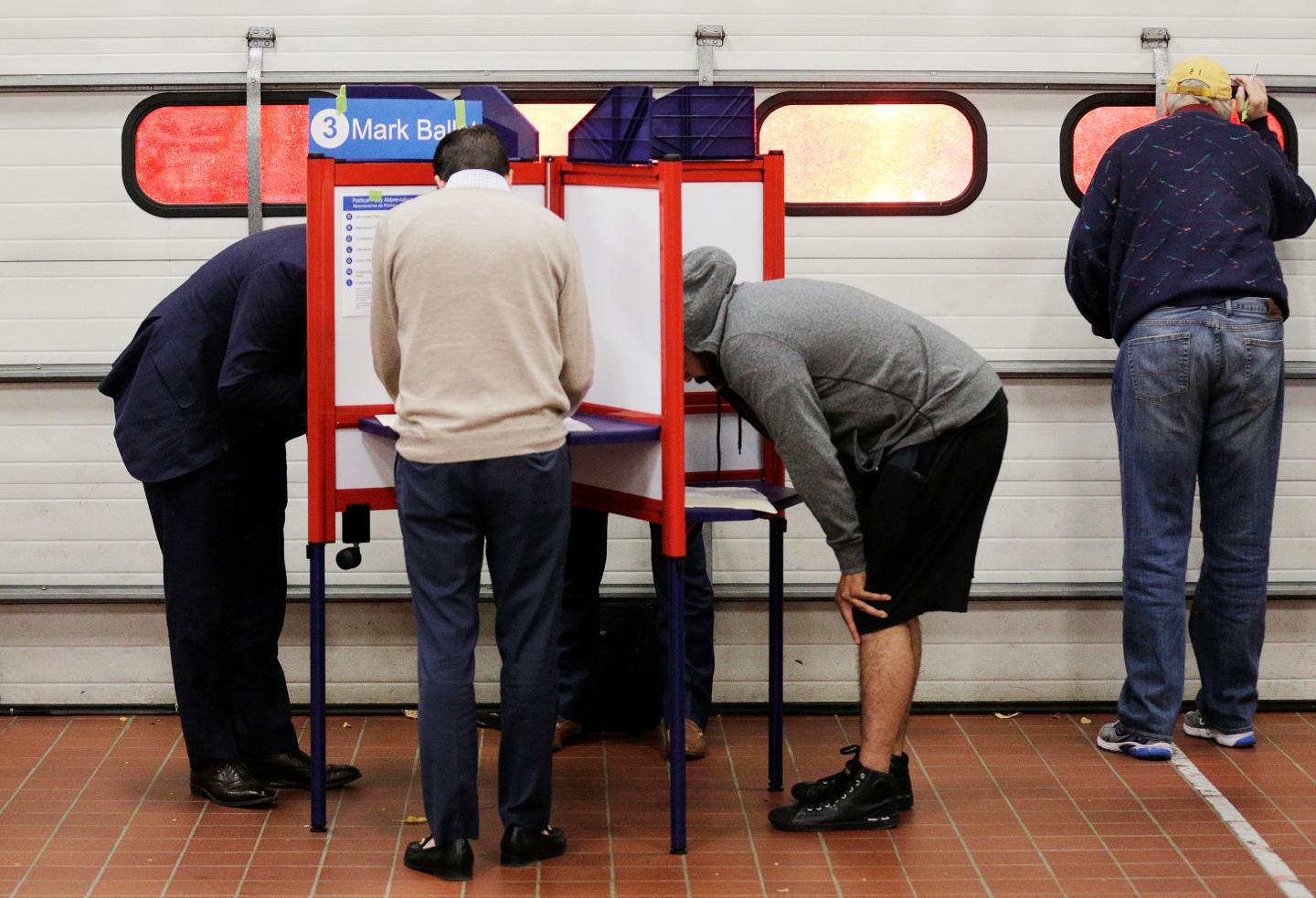 Voters look over their ballots at a fire station while a crew leaves on an emergency call during the U.S. presidential election in Arlington