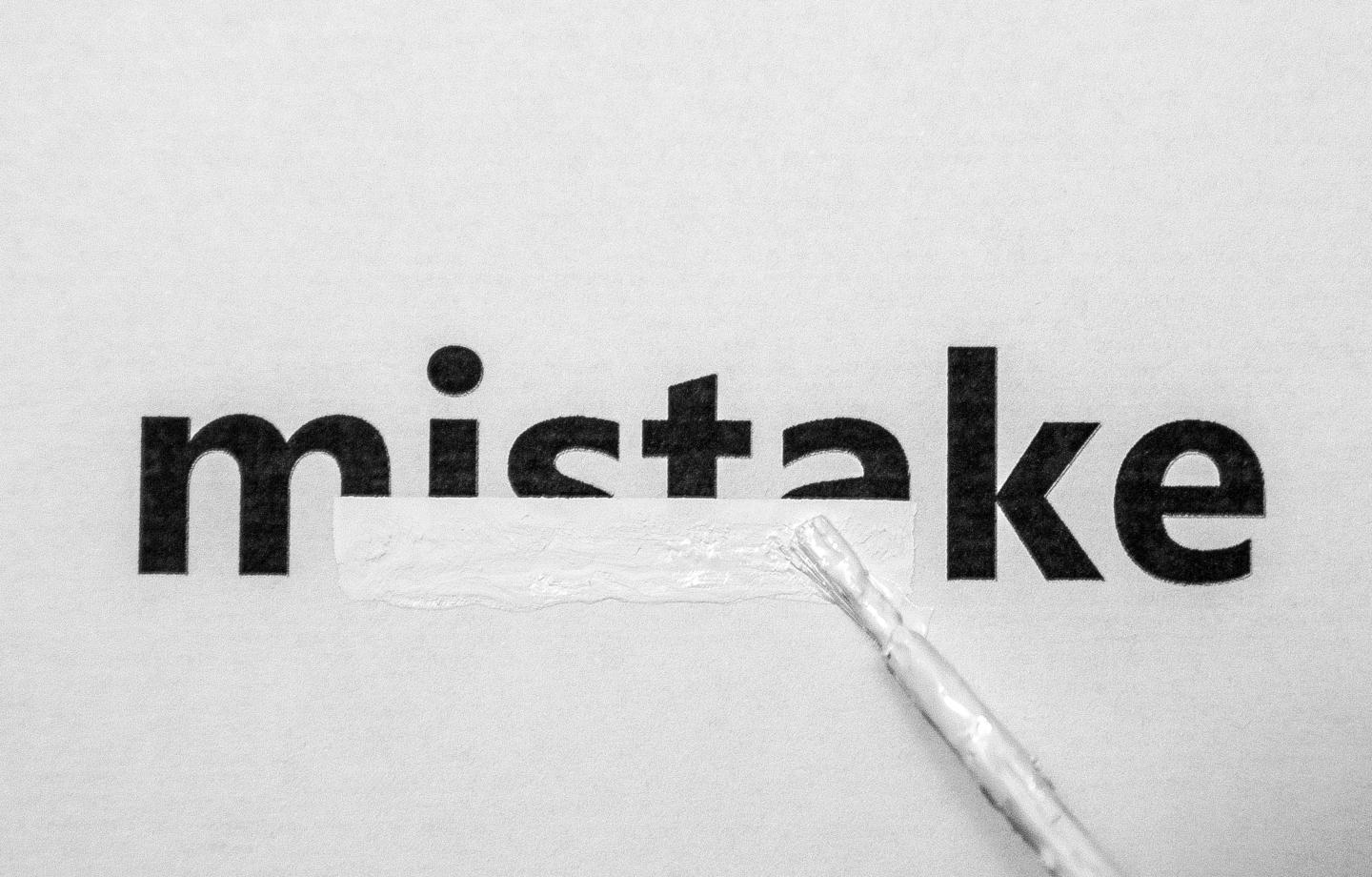 A paintbrush covering up mistake with white paint