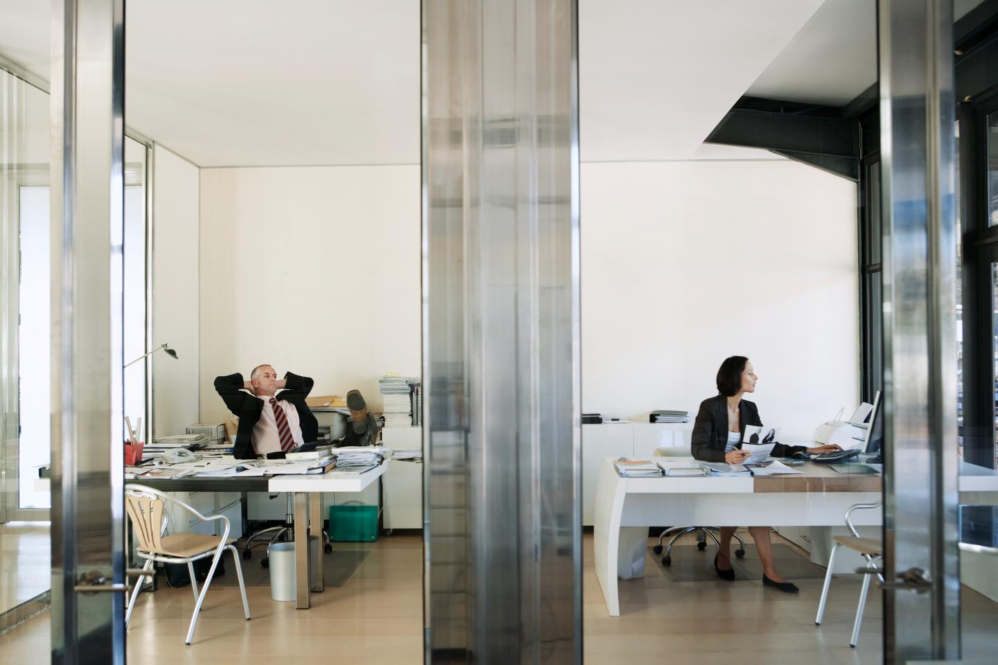 Businessman Relaxing as Businesswoman Works