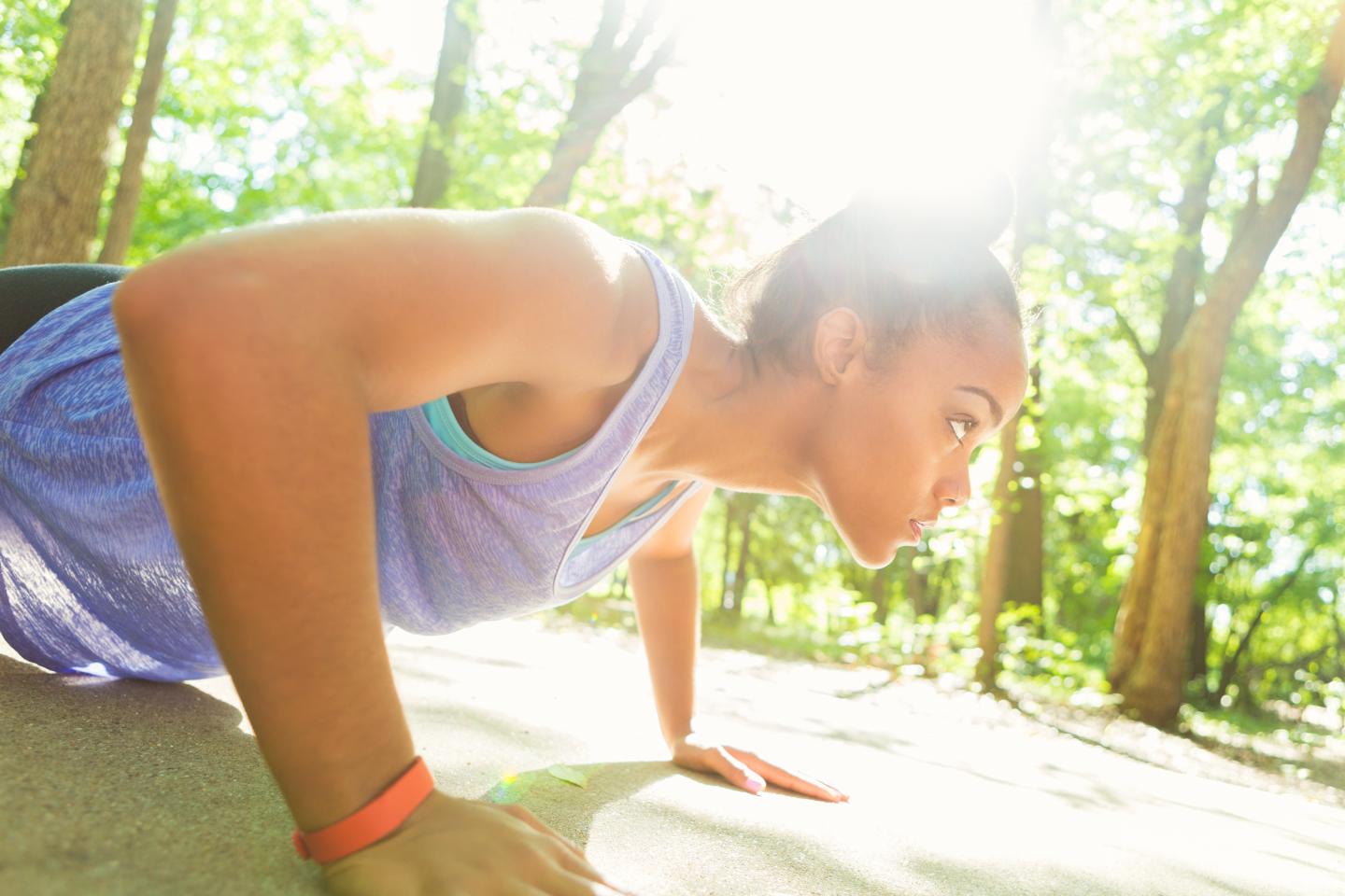 Athletic African American woman doing push ups on sunny day