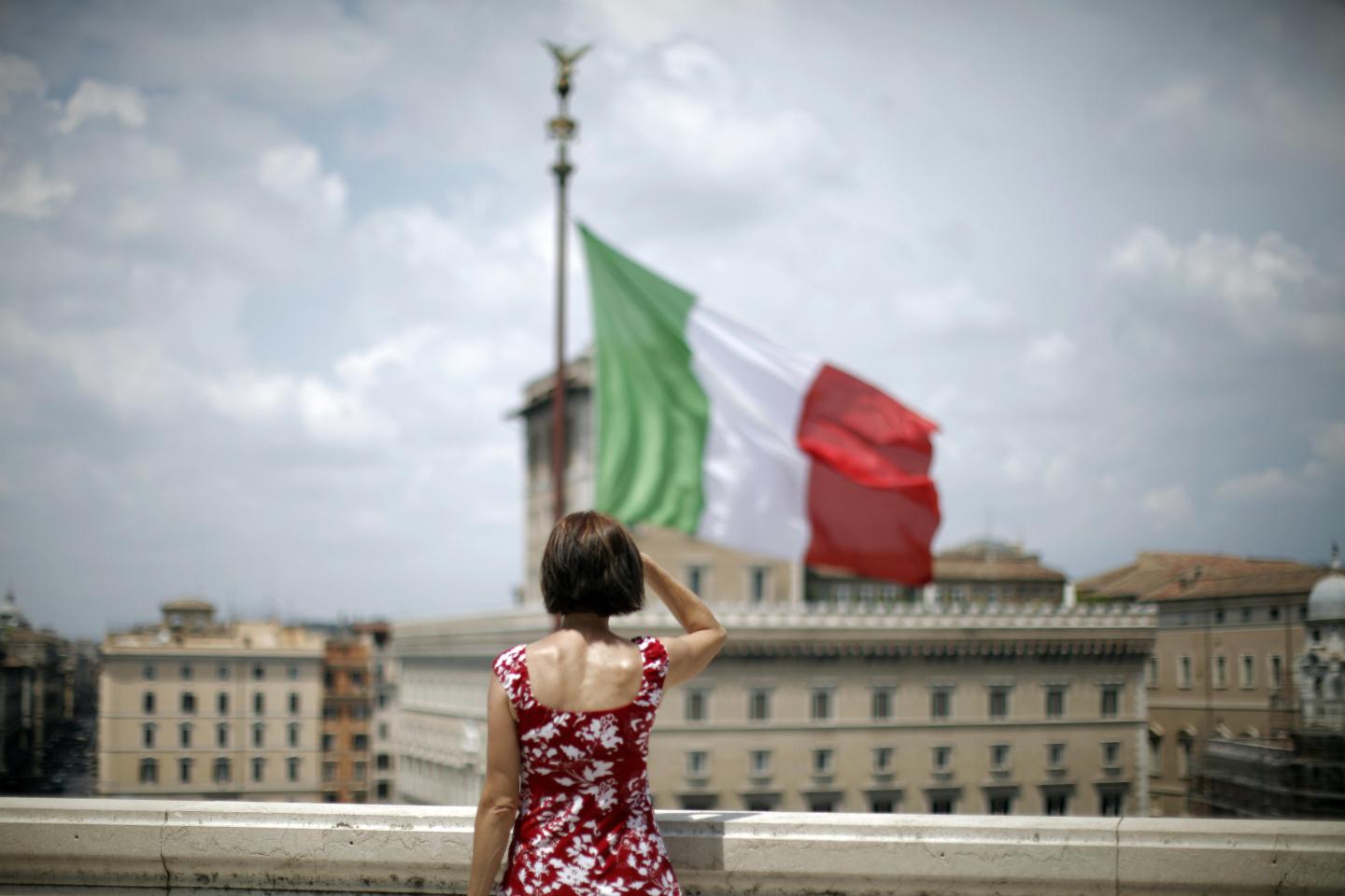 A woman stands in front of a waving Ital