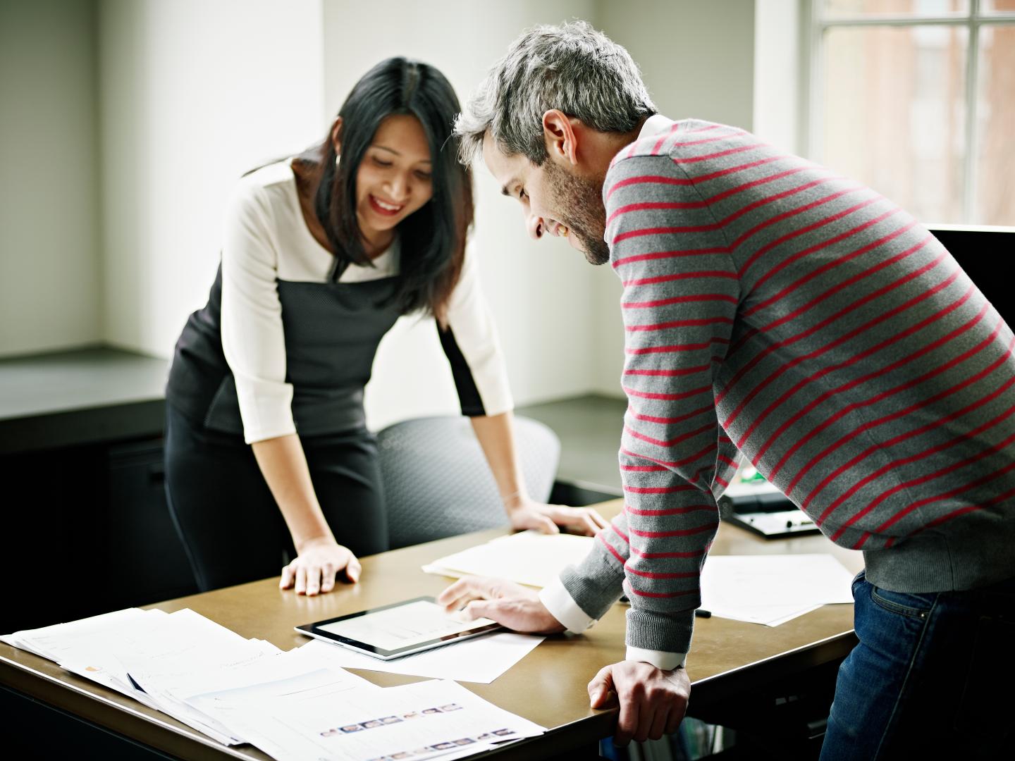 Coworkers analyzing data on digital tablet on desk