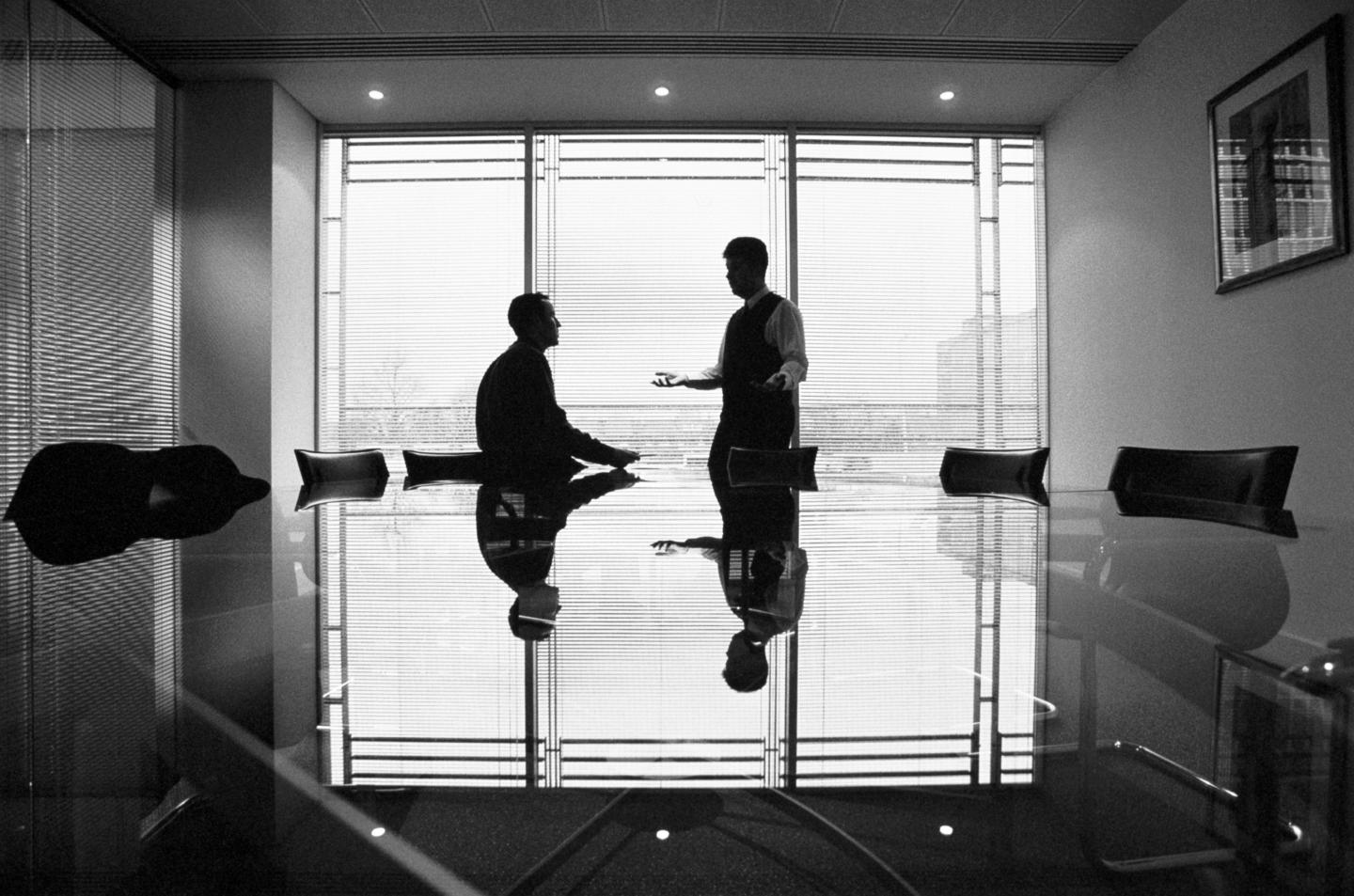 Two businessmen talking in conference room, silhouette (B&amp;W)