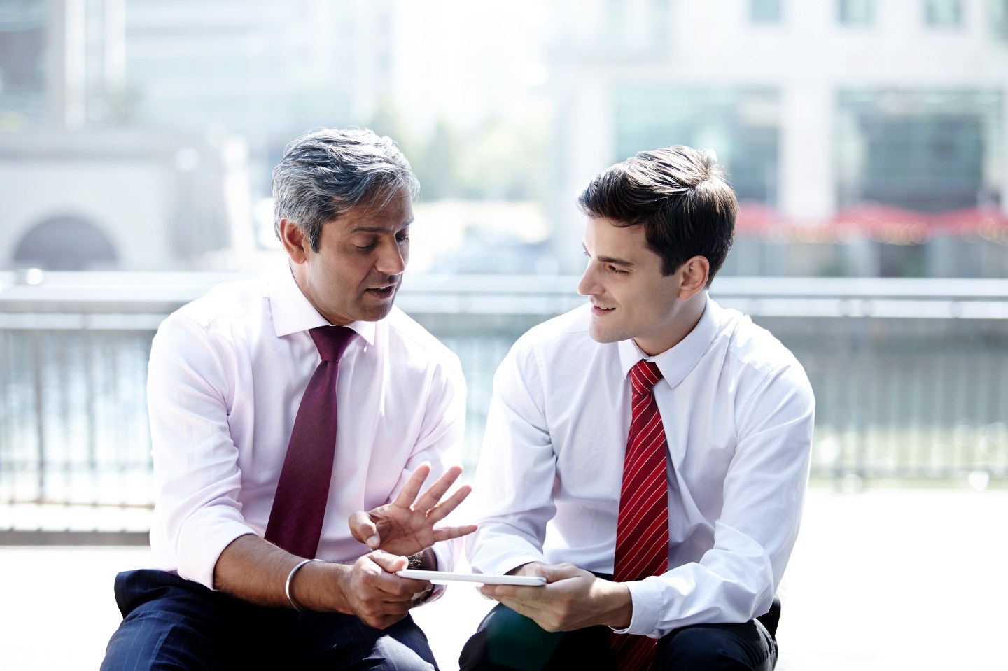 Two businessmen working on a digital tablet.