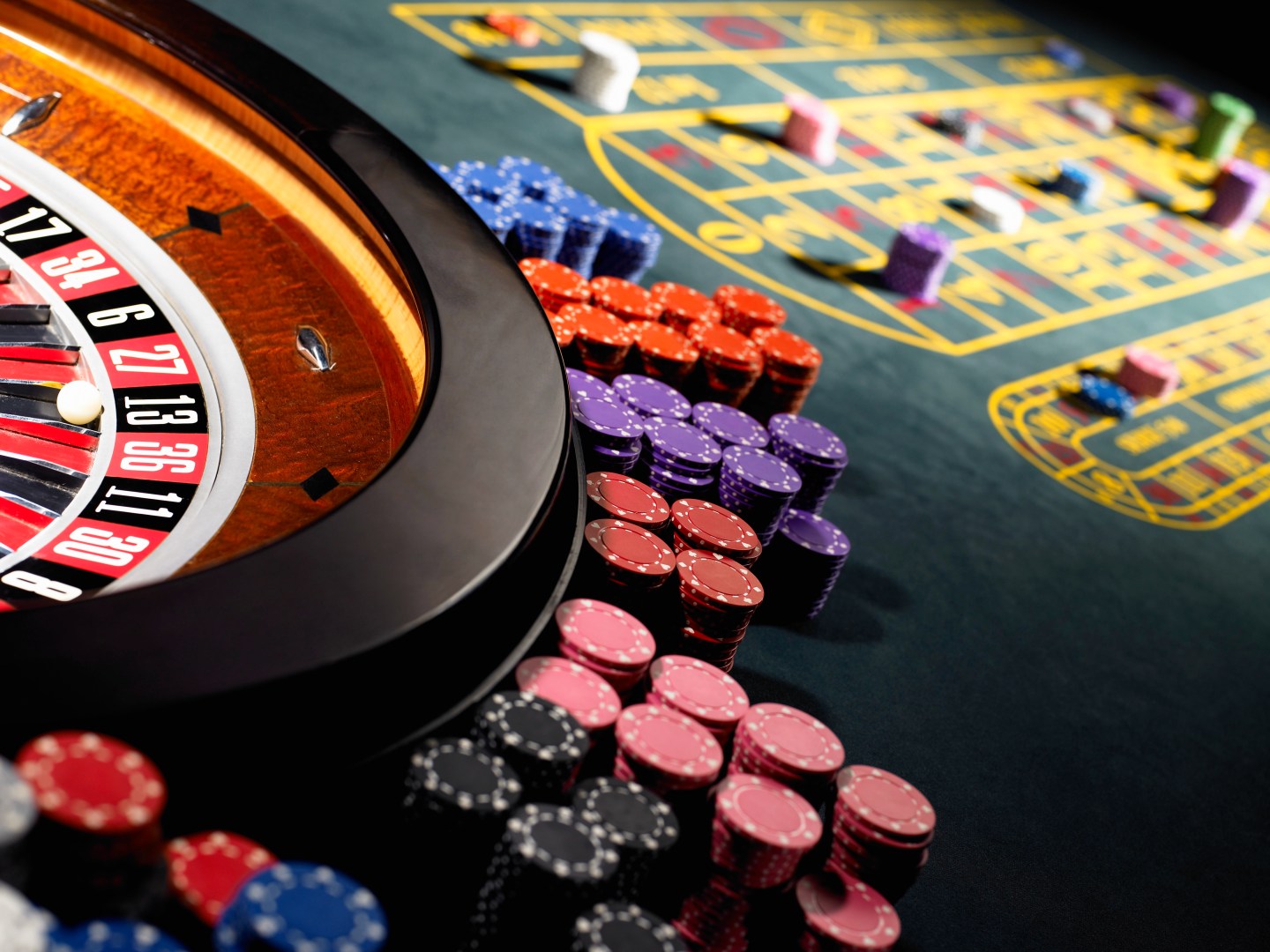 Gambling chips stacked around roulette wheel on gaming table
