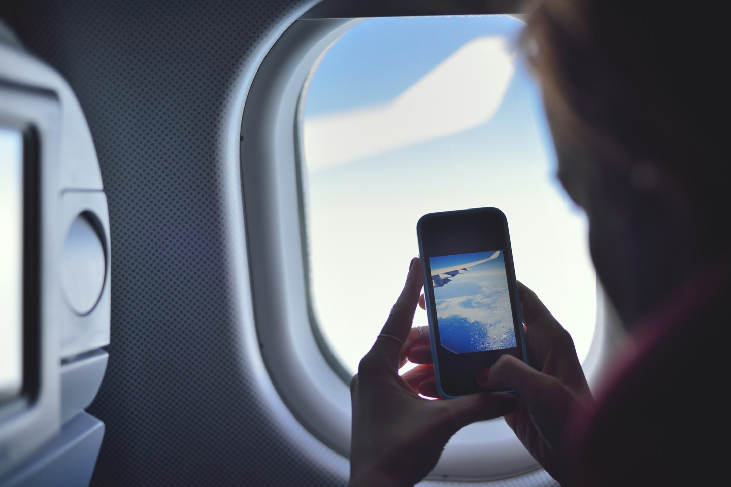 Young woman taking a picture on an airplane
