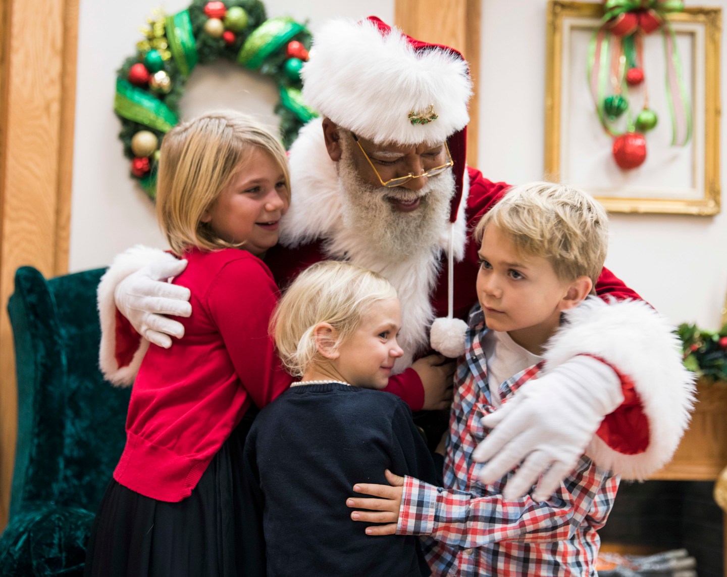 Larry Jefferson, playing the role of Santa, gets a hug from Olivia Major, left, her sister Mallory and brother Preston, of Blaine, at the Santa Experience at Mall of America in Bloomington, Minn.