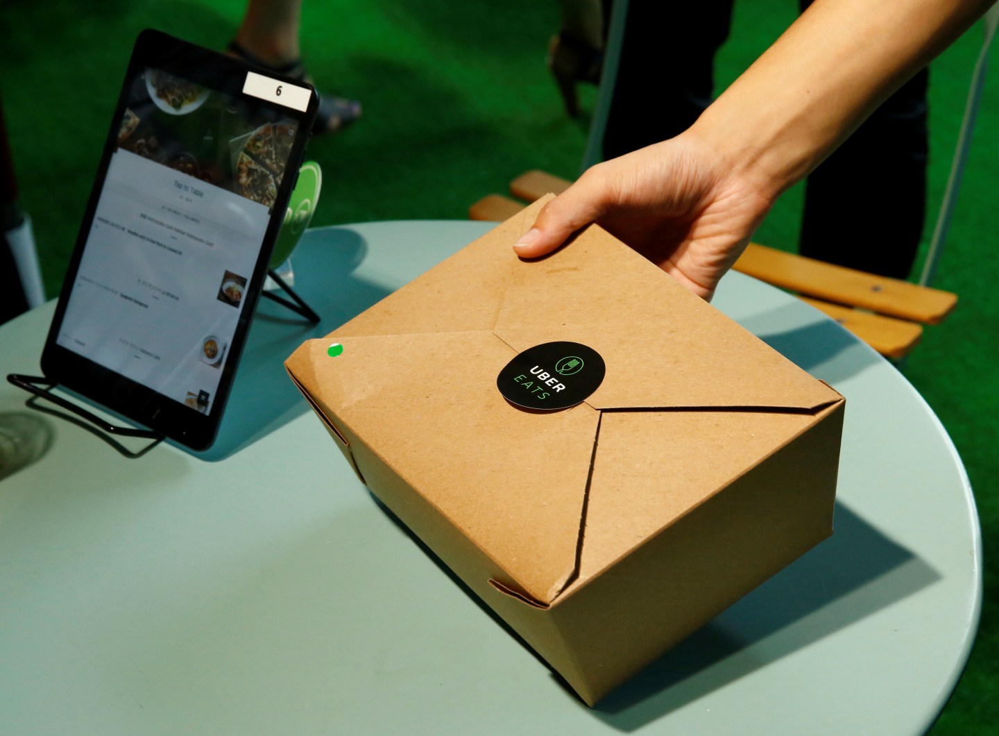 A staff delivers food as he demonstrate a food-delivery service at the launching event of UberEats in Tokyo