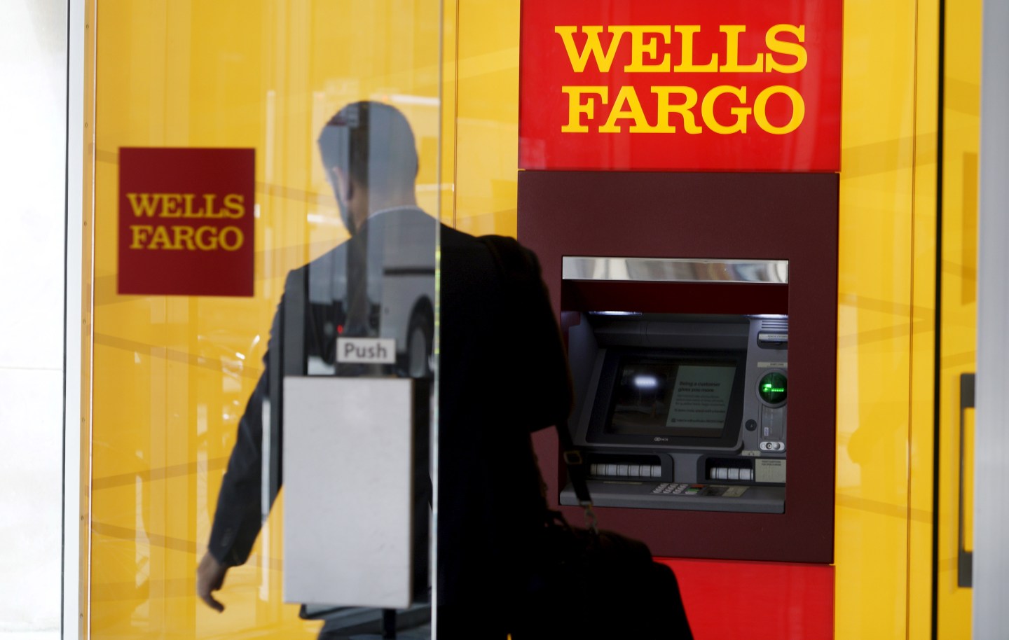 A man walks by a bank machine at the Wells Fargo &amp; Co. bank in downtown Denver