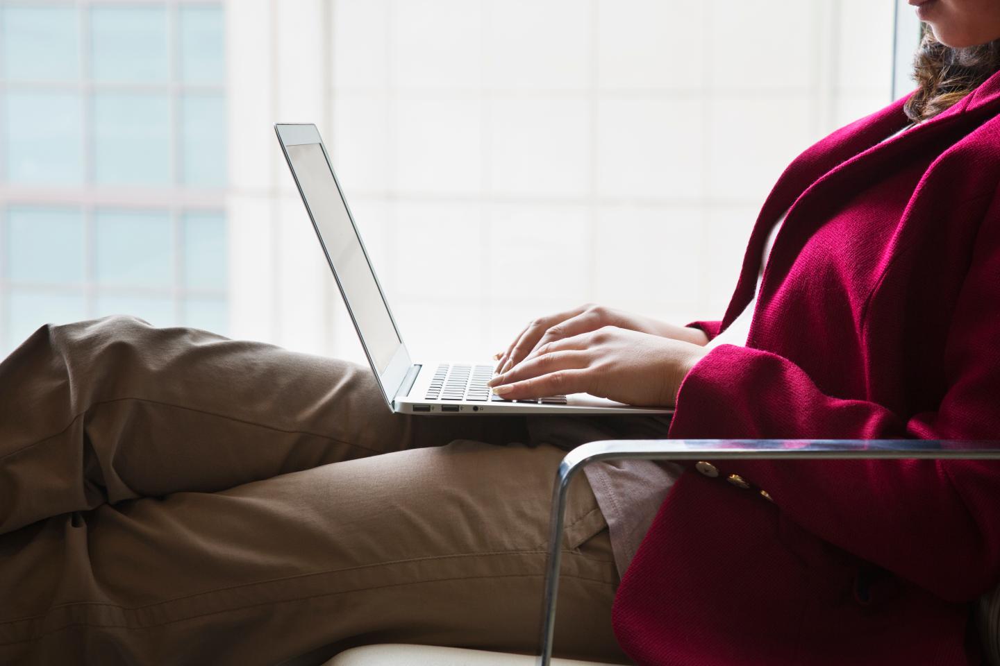 Hispanic woman using laptop in chair