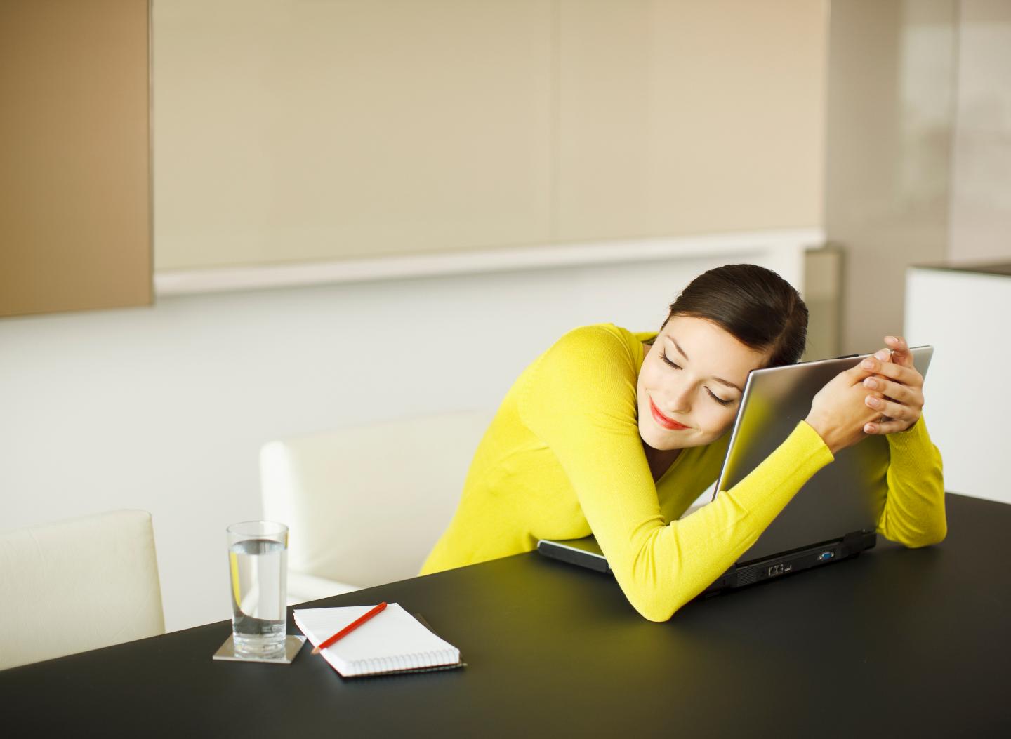 Smiling businesswoman hugging laptop in conference room
