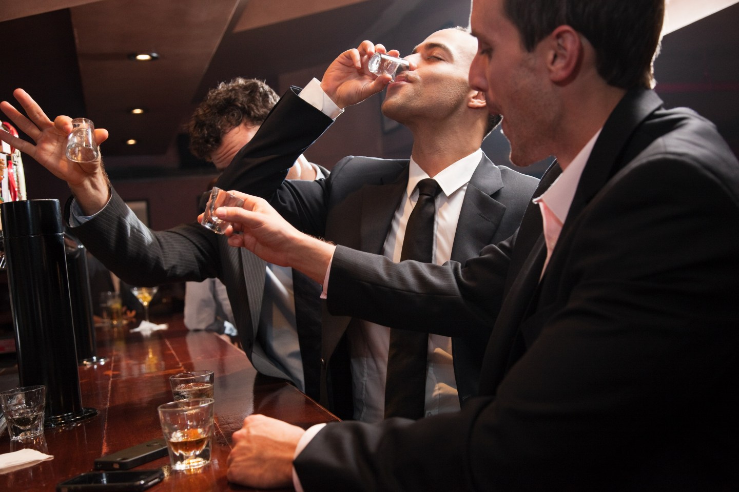 Businessmen drinking shots in bar