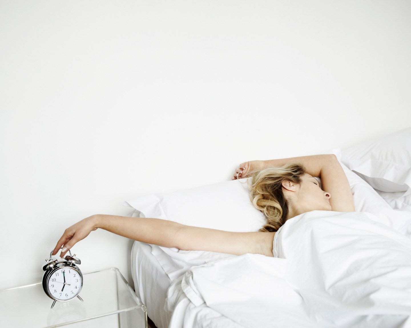 Woman reaching to turn alarm clock off