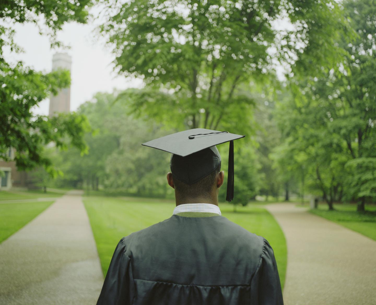 Male college student wearing cap and gown, rear view