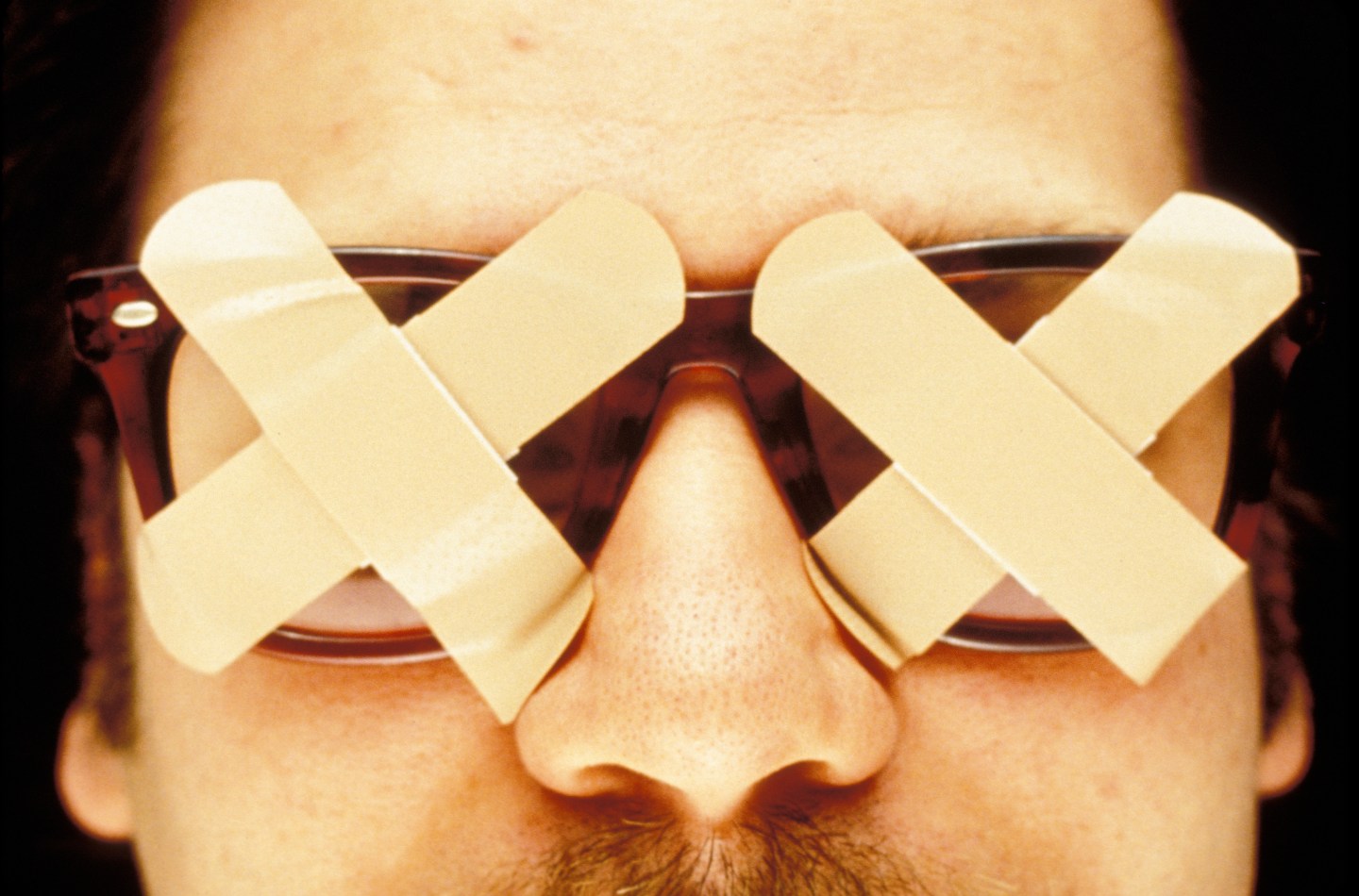 Man wearing glasses covered with bandages