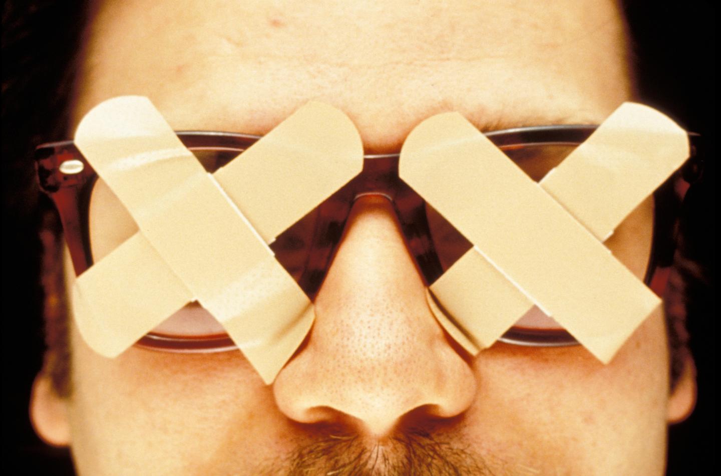 Man wearing glasses covered with bandages